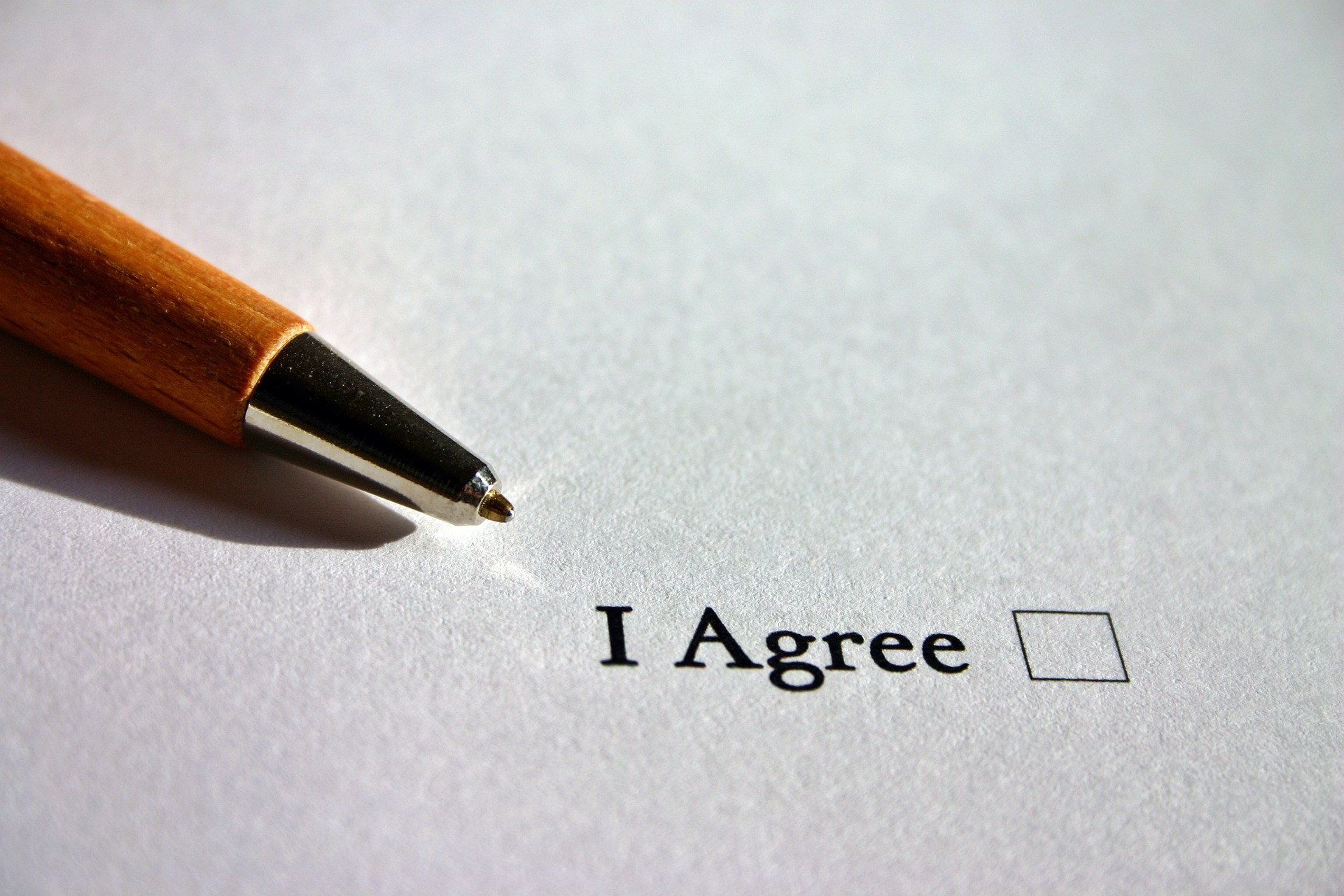 An "I Agree" checkbox written on paper with a pen next to it